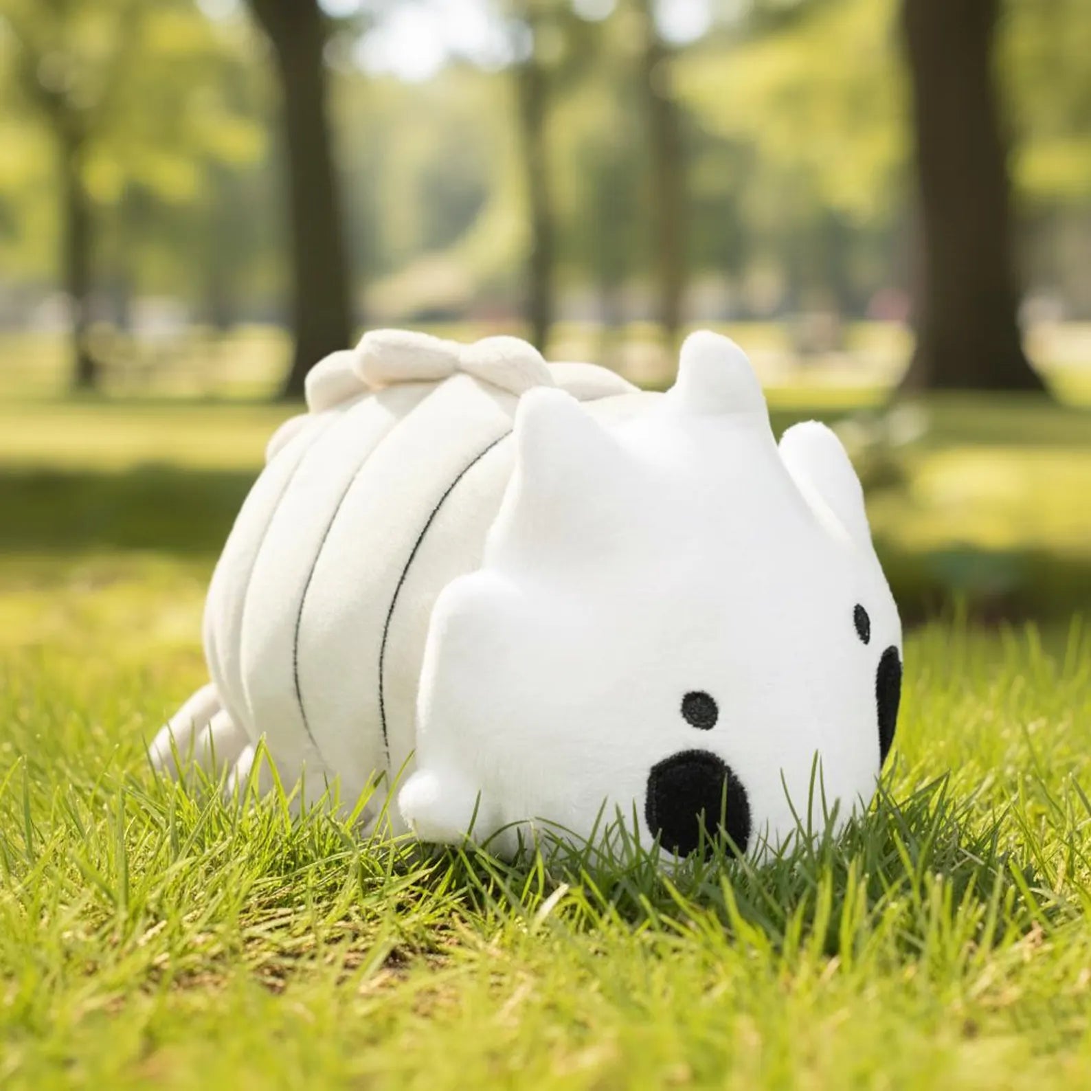 The Bell Beast Plush Toy sitting on the grass
