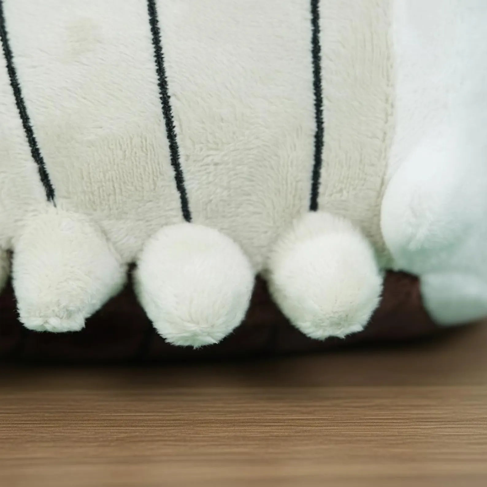 Close-up detail of the Bell Beast Plush Toy's embroidered features and bell accents.
