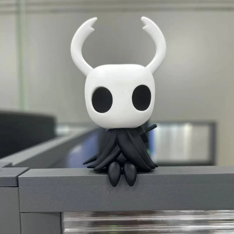 Hollow Knight Mini Figure placed on an office desk next to a pen, showcasing its use as a charming desktop ornament.