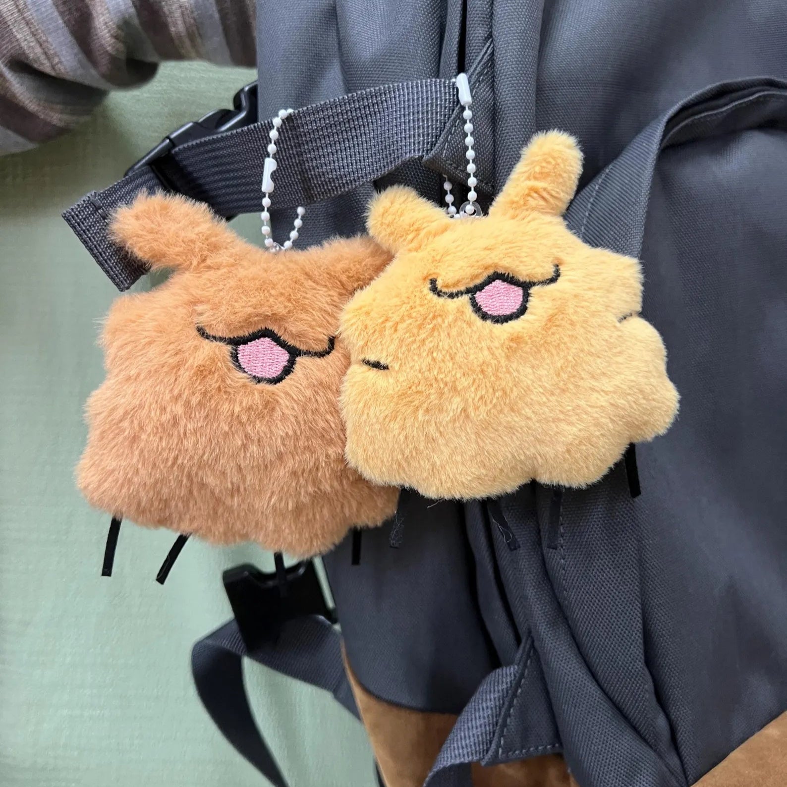The Squeaky Silksong Flea Plush attached to a backpack zipper, showing it used as a durable backpack charm