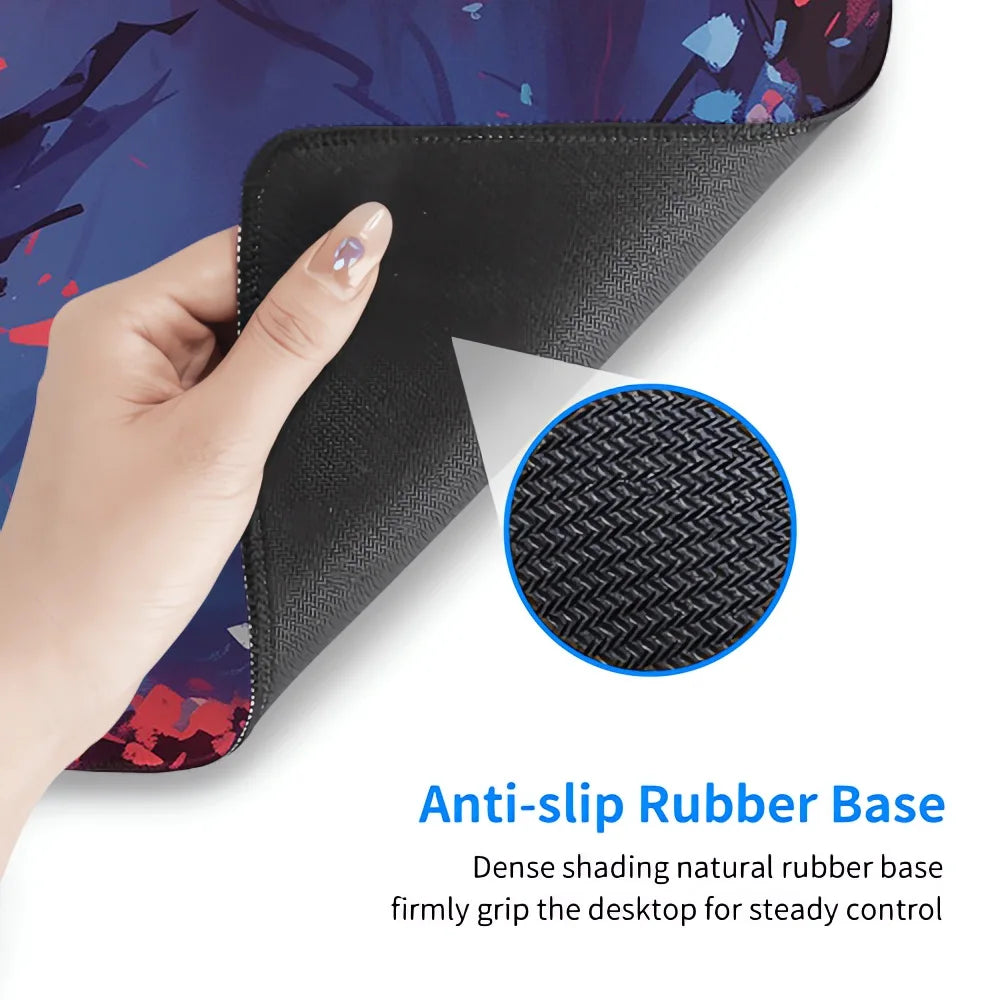 A hand lifts the corner of a printed desk mat to show the black anti-slip rubber base, with a circular inset close-up of the textured rubber and text reading 'Anti-slip Rubber Base.'.