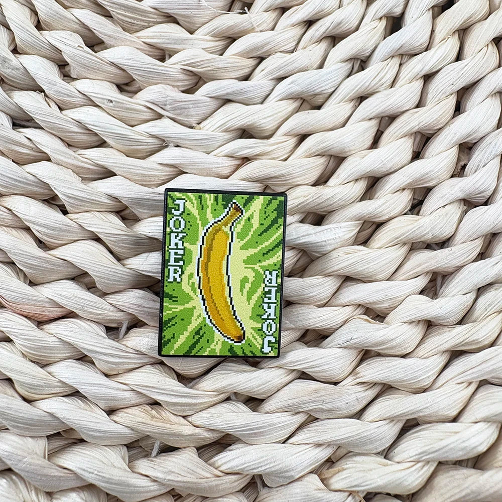 Banana Joker card pin on a woven surface