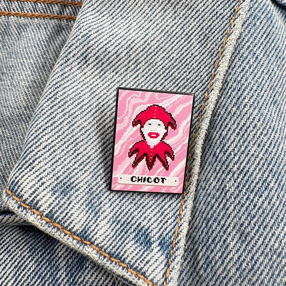 Pin with a Chicot Joker design on a pink background, attached to a denim jacket.
