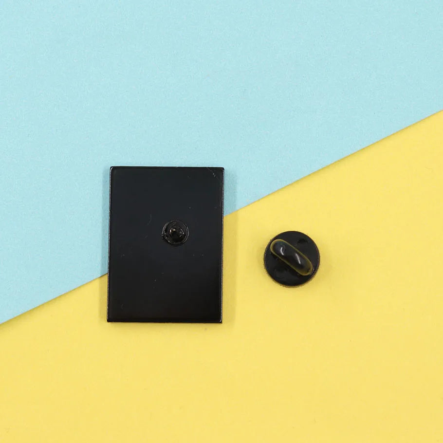 Black square object and round pin on a yellow and blue background