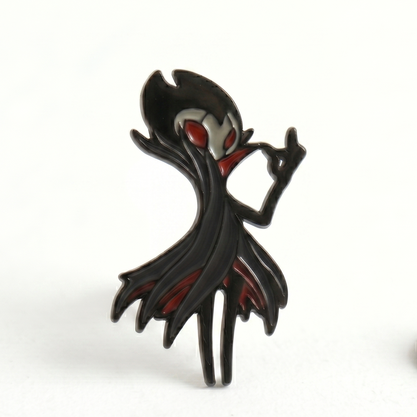 Detailed close-up of the red and black enamel pin on the Hollow Knight Grimm accessory.