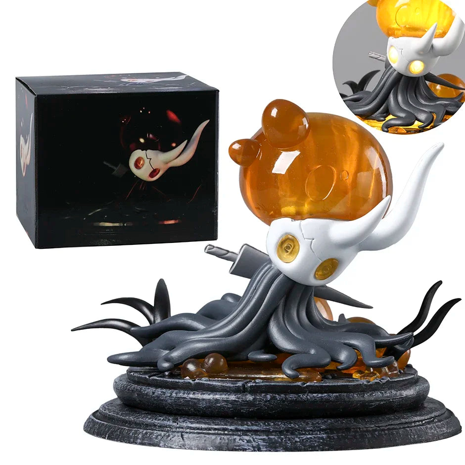 Hollow Knight Broken Vessel figurine with a black base, next to a black box with a smaller figurine inside.
