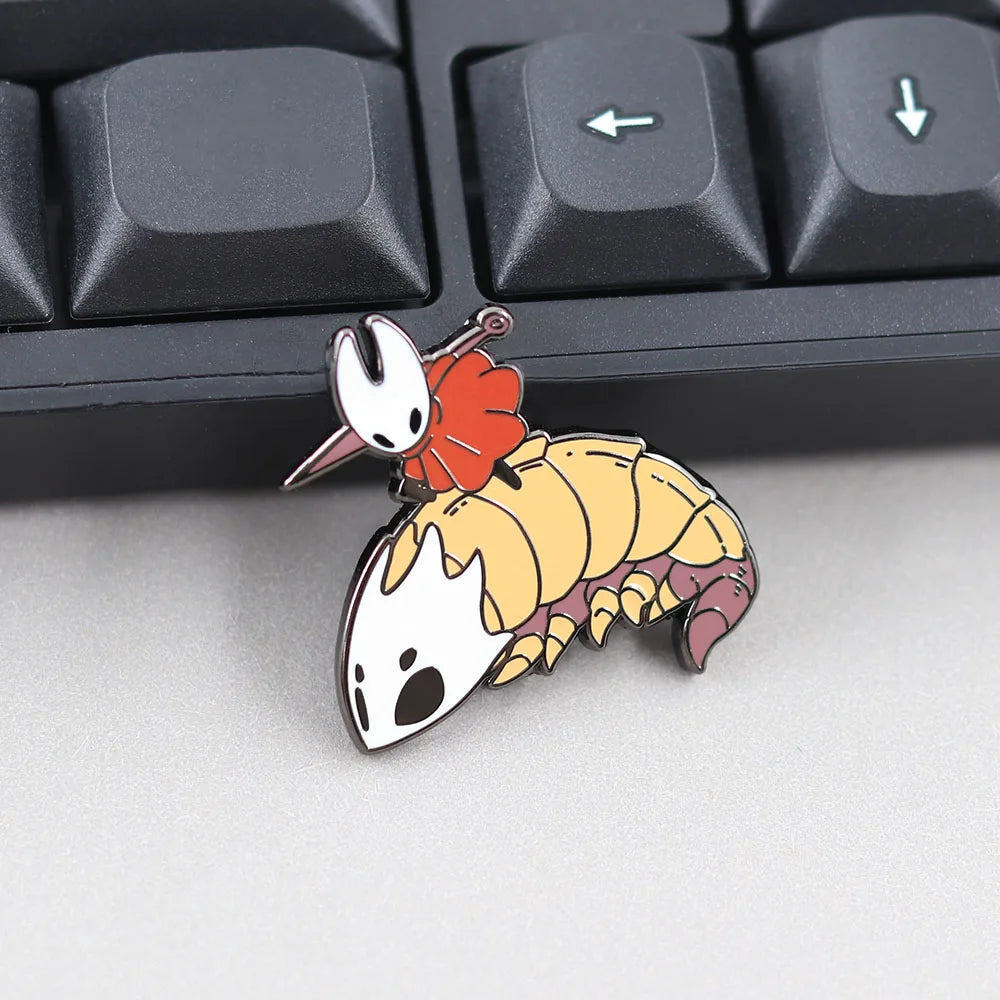 The Hornet & Bell Beast enamel pin on a desk with keyboards