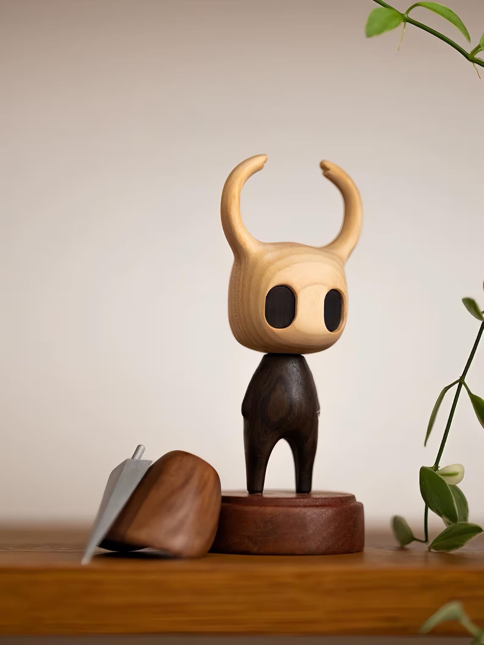 Hollow Knight Wooden figurine with large ears on a wooden base against a neutral background