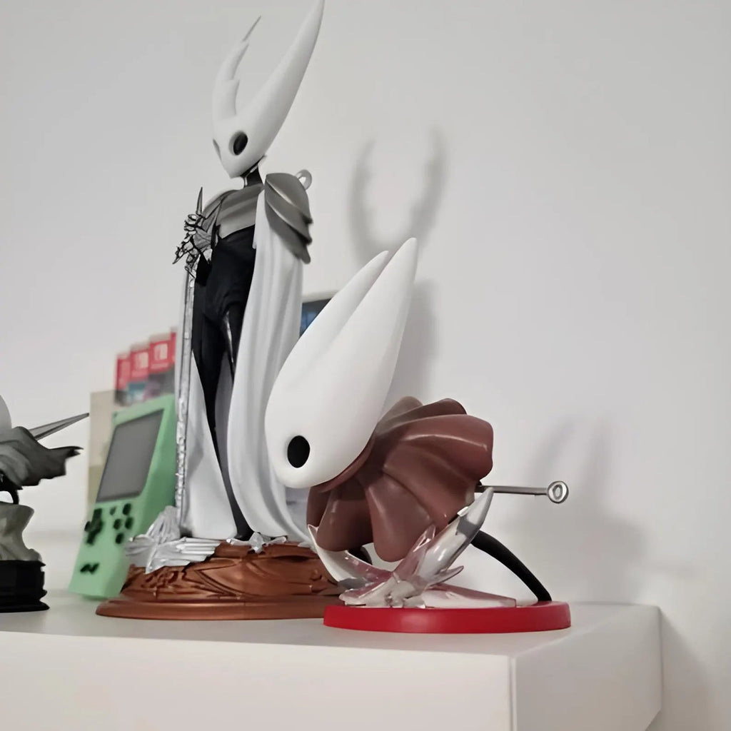 Hornet figure displayed on a gaming desk with a monitor showing a screenshot from Hollow Knight: Silksong.