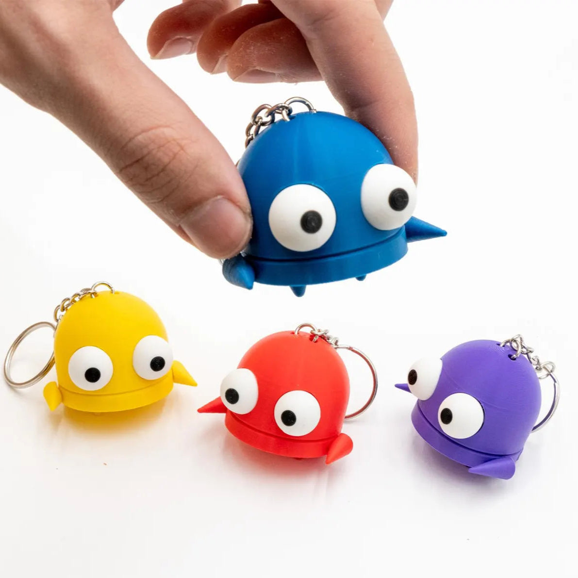 Four colorful keychains shaped like R.E.P.O. characters with googly eyes on a white background.