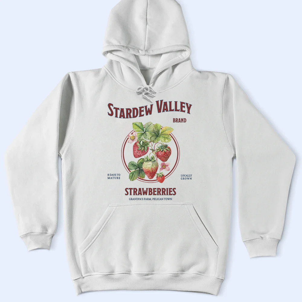 White hoodie with 'Stardew Valley' strawberry label design on a light blue background